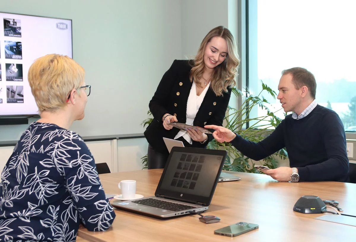 Three TIGER employees gathered around a table engaged in conversation and seated comfortably.