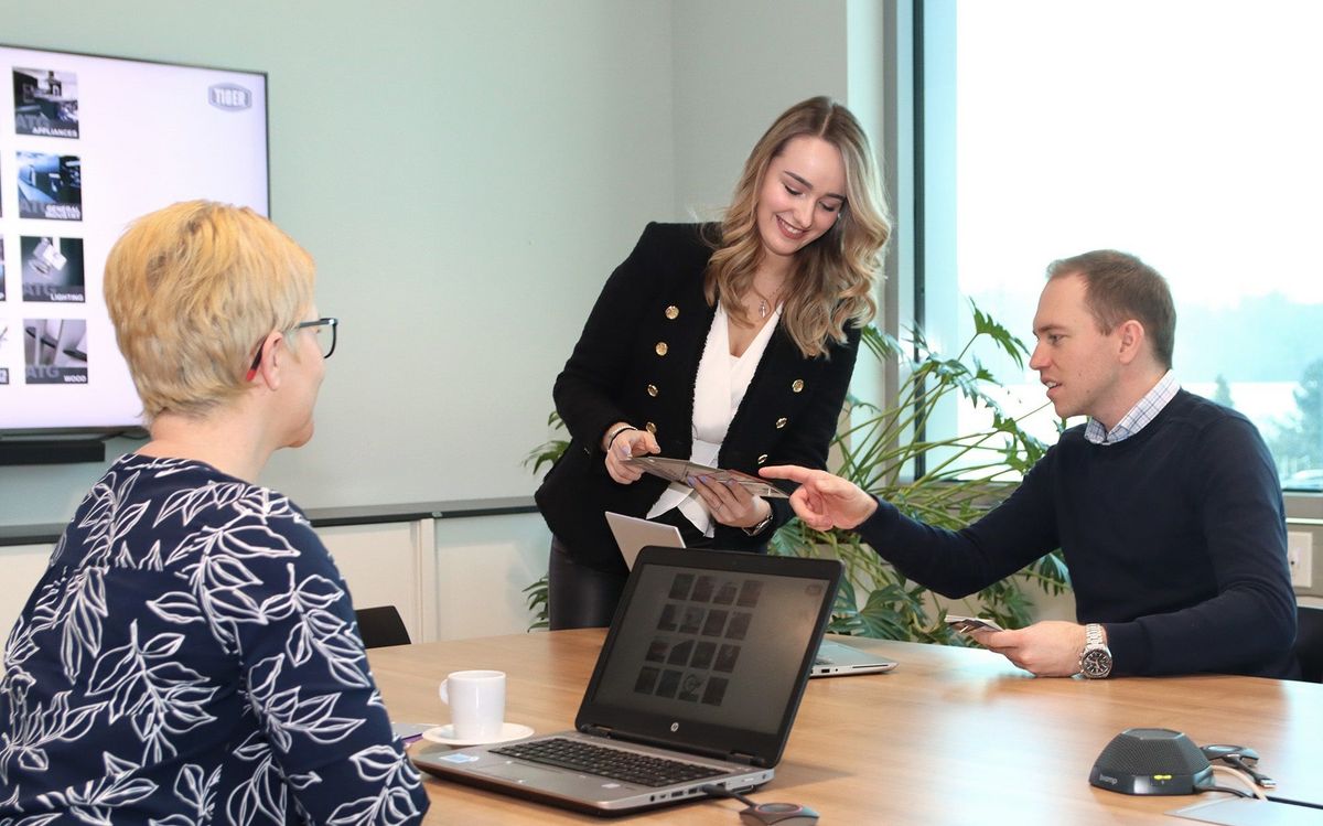 Three TIGER employees gathered around a table engaged in conversation and seated comfortably.