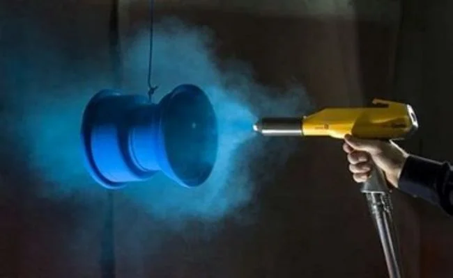blue powder coating being sprayed with a gun on a circular object