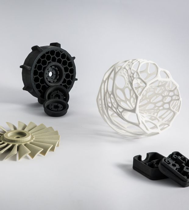 5 3D-gedruckte Komponenten, hergestellt durch SLS-Druck mit Thermoset-Pulvern. Die Objekte bestehen aus 2 Turbinen auf der linken Seite. Eine Ringstruktur in der Mitte. Eine 3-dimensionale, teilweise hohle Kugel und Clips ganz rechts