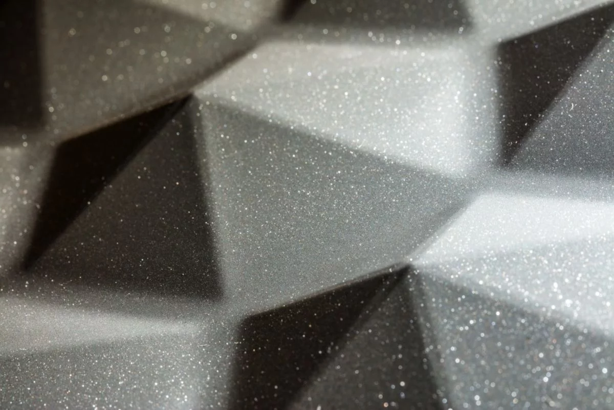 Close-up of a black, metallic metal surface that sparkles in the light